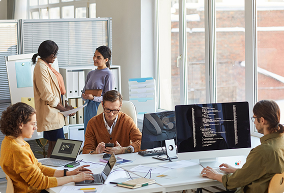 Colleagues collaborating at desks by a window
